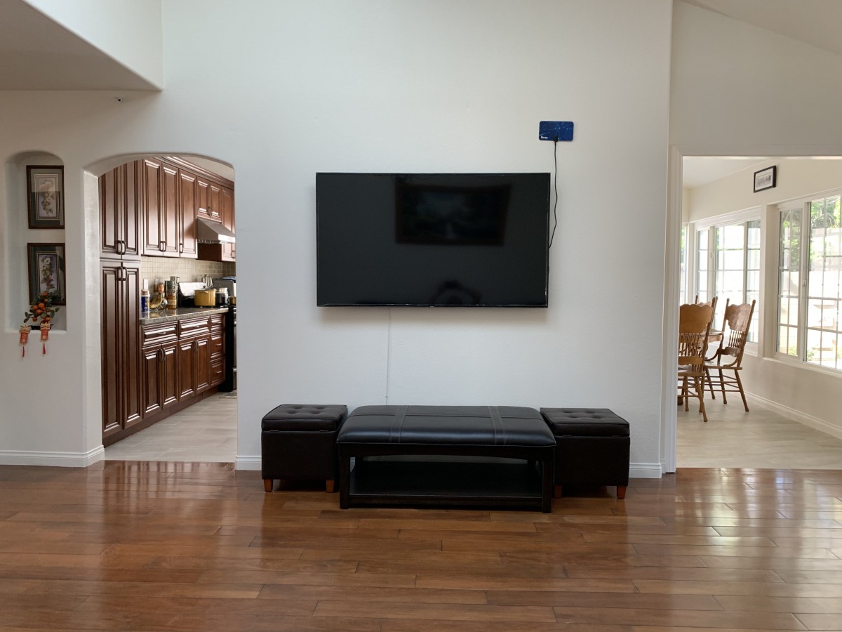 A modern living room with a mounted television, leather seating, and adjoining kitchen area.