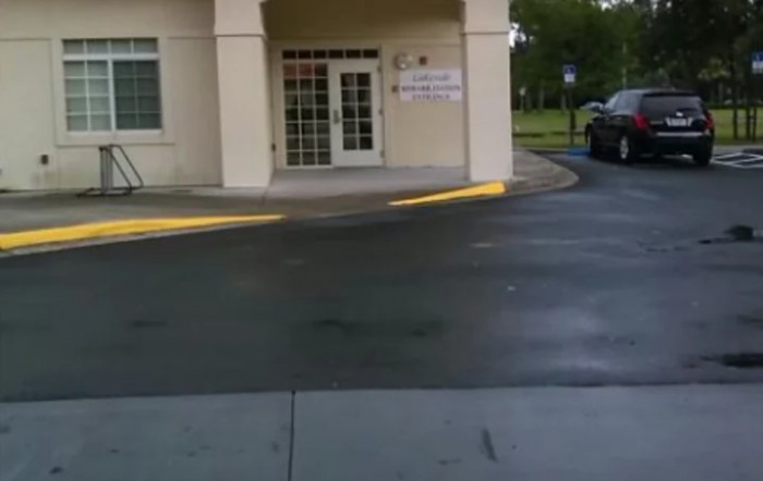 An entrance to a building with an adjacent driveway and parking lot.