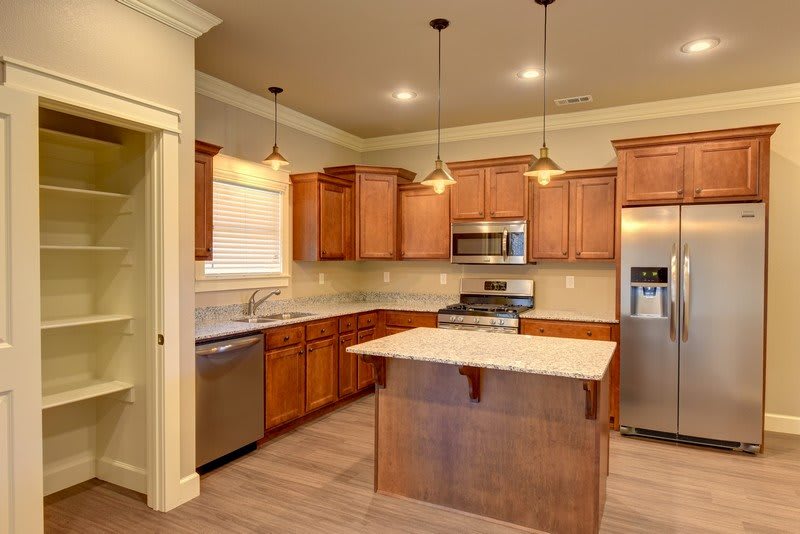 A modern kitchen with wooden cabinets, an island, and stainless steel appliances.