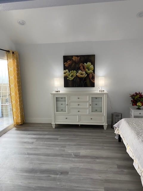 A minimalist bedroom with a white dresser, lamps, and floral artwork.
