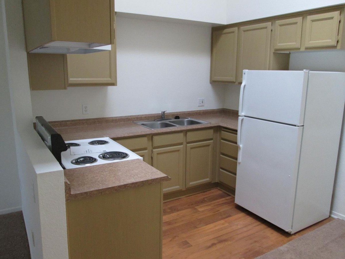 A kitchen with olive green cabinets, a white fridge, and an electric stove.