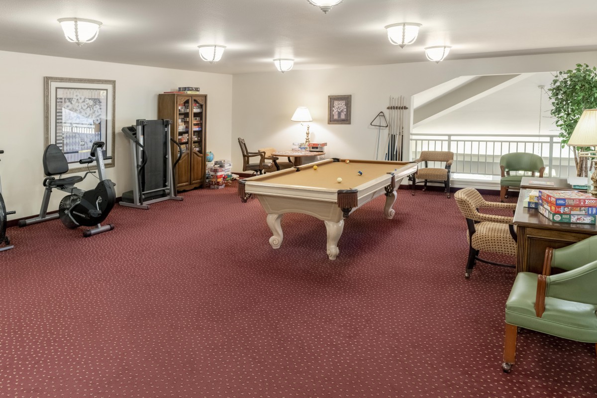 A spacious game room with a pool table and seating area.