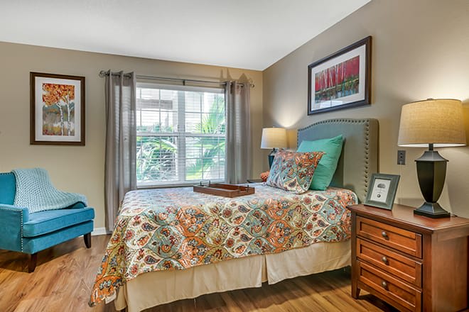 A cozy, well-decorated bedroom featuring a colorful bedspread and large window.