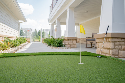 A well-maintained putting green with a yellow flag, set in a spacious outdoor area.