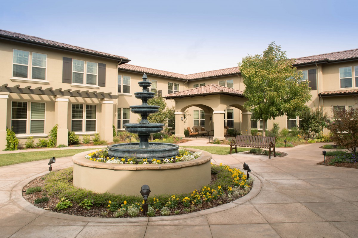 A beautifully landscaped courtyard with a central fountain and surrounding greenery.