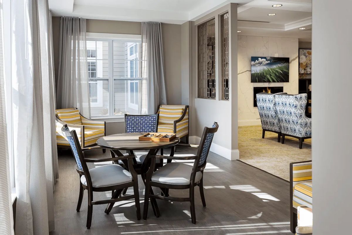 A cozy living area with a table and chairs near a large window.