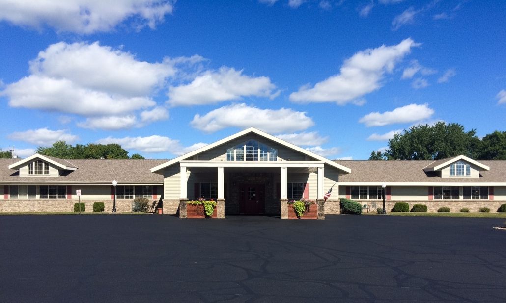 A wide-angle view of a building with a clear blue sky and scattered clouds.