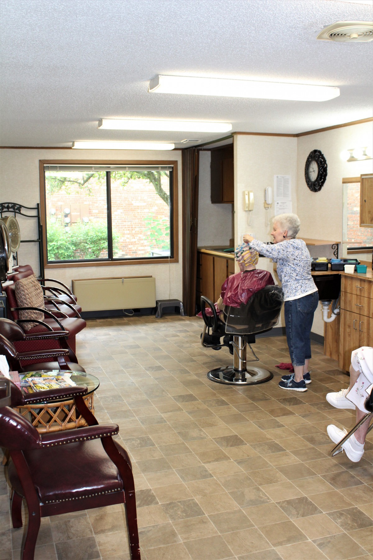 A hairdresser styling an elderly client's hair in a cozy salon.