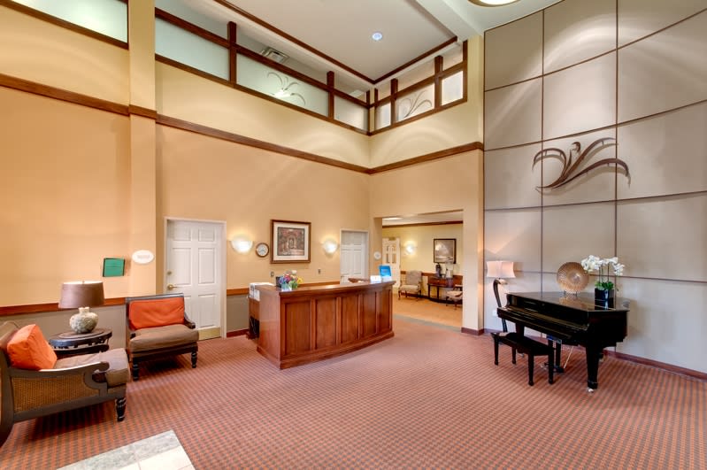 A hotel lobby with a reception desk, seating area, and grand piano.