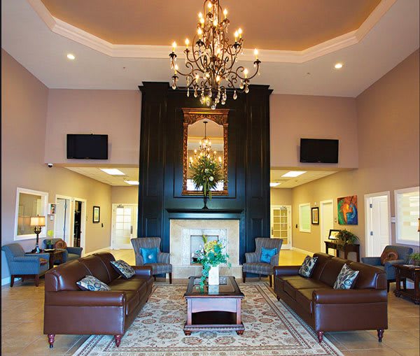 A luxurious lobby featuring a central chandelier, comfortable sofas, and an elegant fireplace.