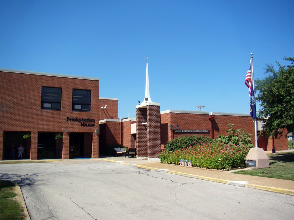 A brick church building with a prominent steeple and flags outside.