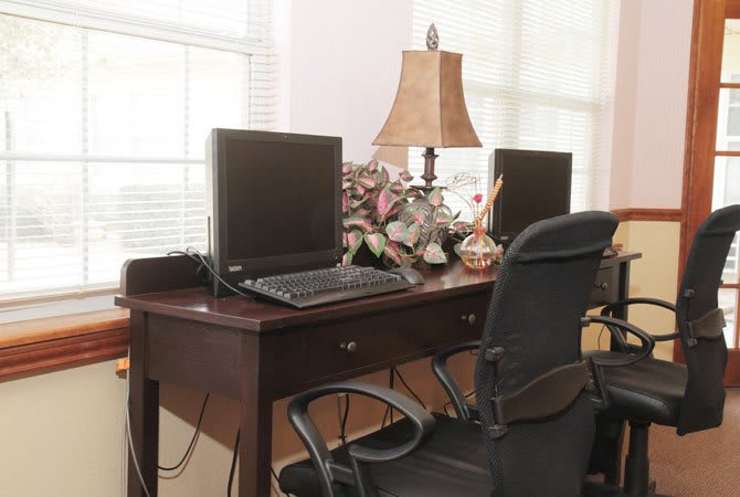 A tidy office desk with computers and a lamp.
