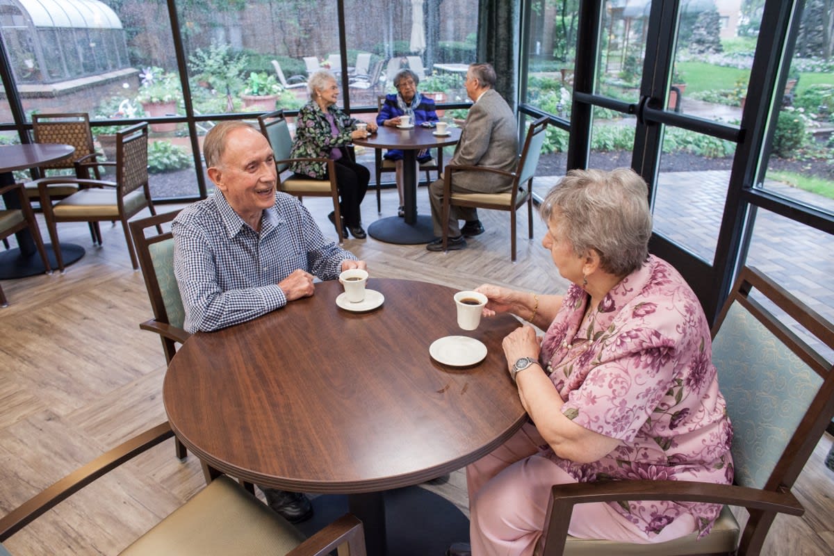 Elderly couples enjoying coffee and conversation in a cozy cafe setting.