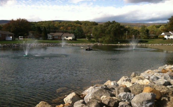 A scenic view of a lake with fountains and surrounding greenery.