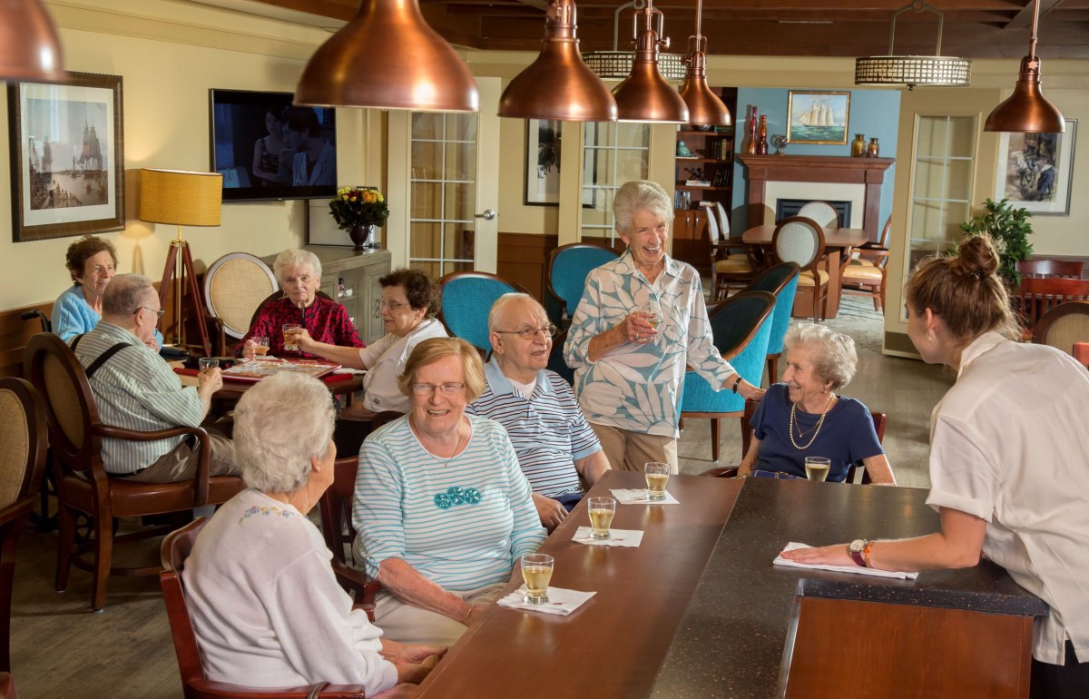 A group of seniors socializing in a community room setting.