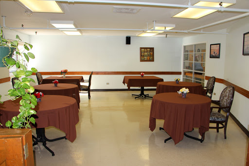A spacious dining area with round tables covered in brown tablecloths, set in a well-lit room.