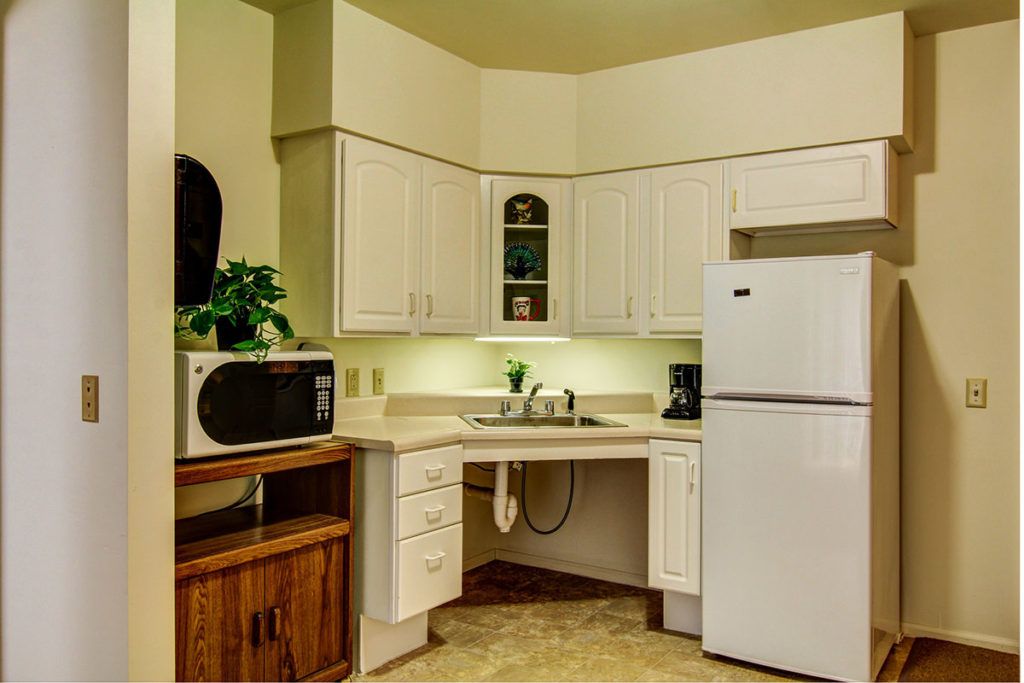 A modern kitchen with white cabinets, a refrigerator, microwave, and sink.