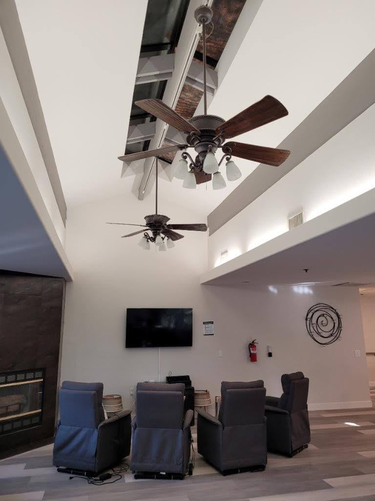A modern living room interior featuring ceiling fans, a television, and comfortable seating.