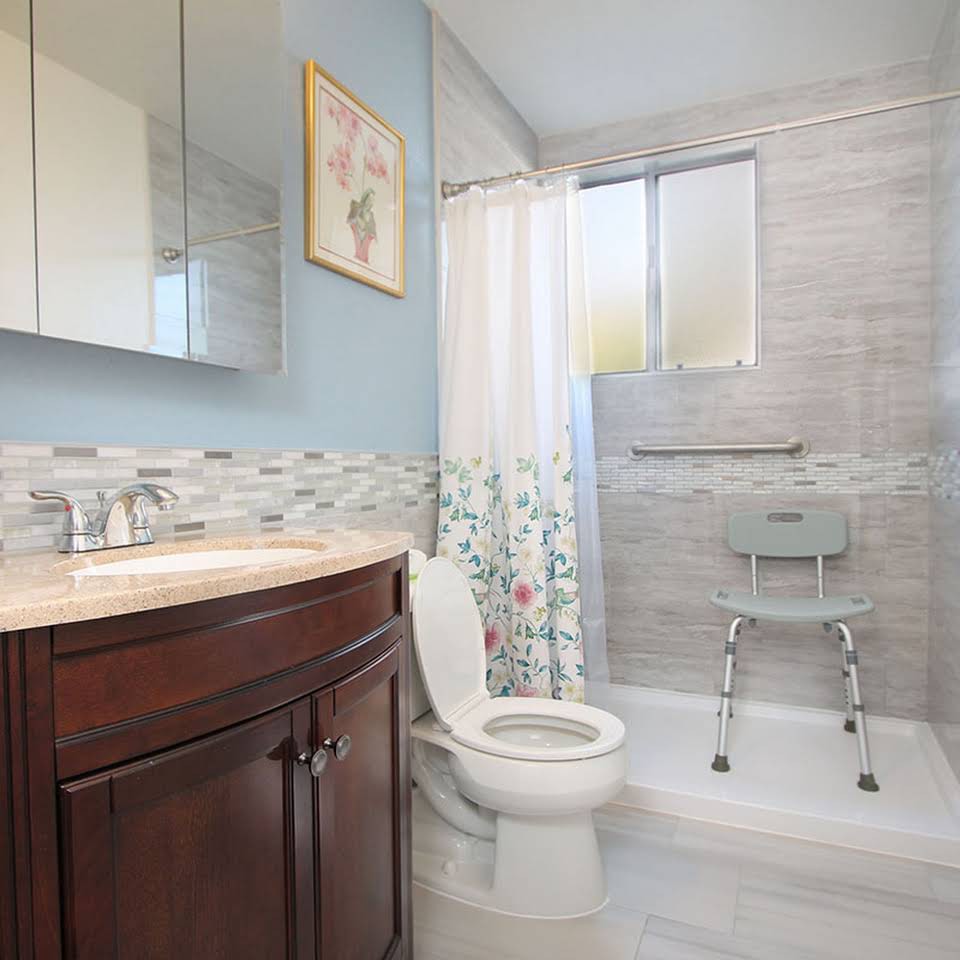A modern bathroom featuring a toilet, shower, and vanity with a mirror.