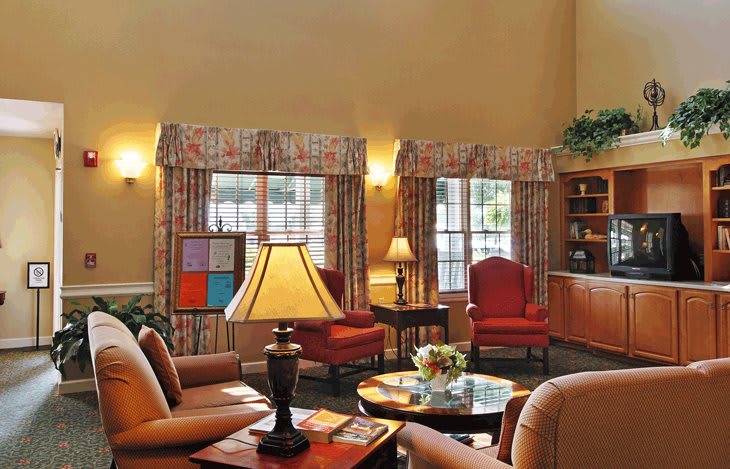A cozy living room featuring chairs, sofas, and lamps with natural light flowing through the windows.