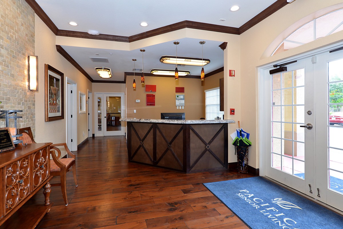 A welcoming reception area with a wooden floor, front desk, and ceiling lights.