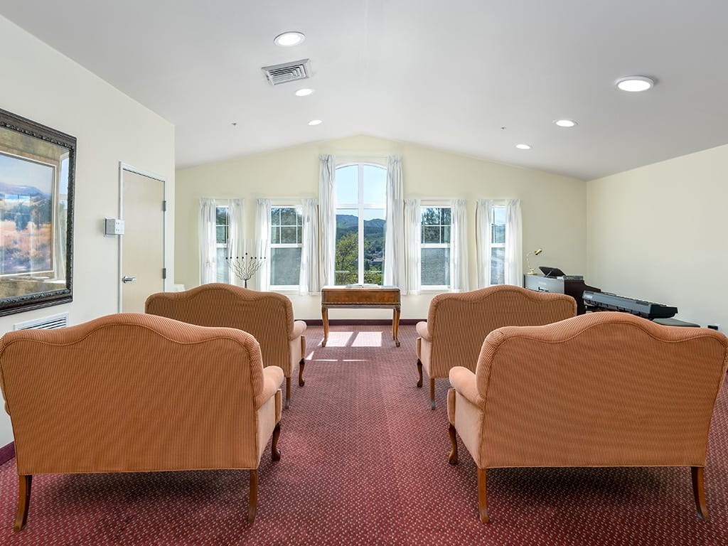 A well-lit room with chairs arranged facing a set of windows.