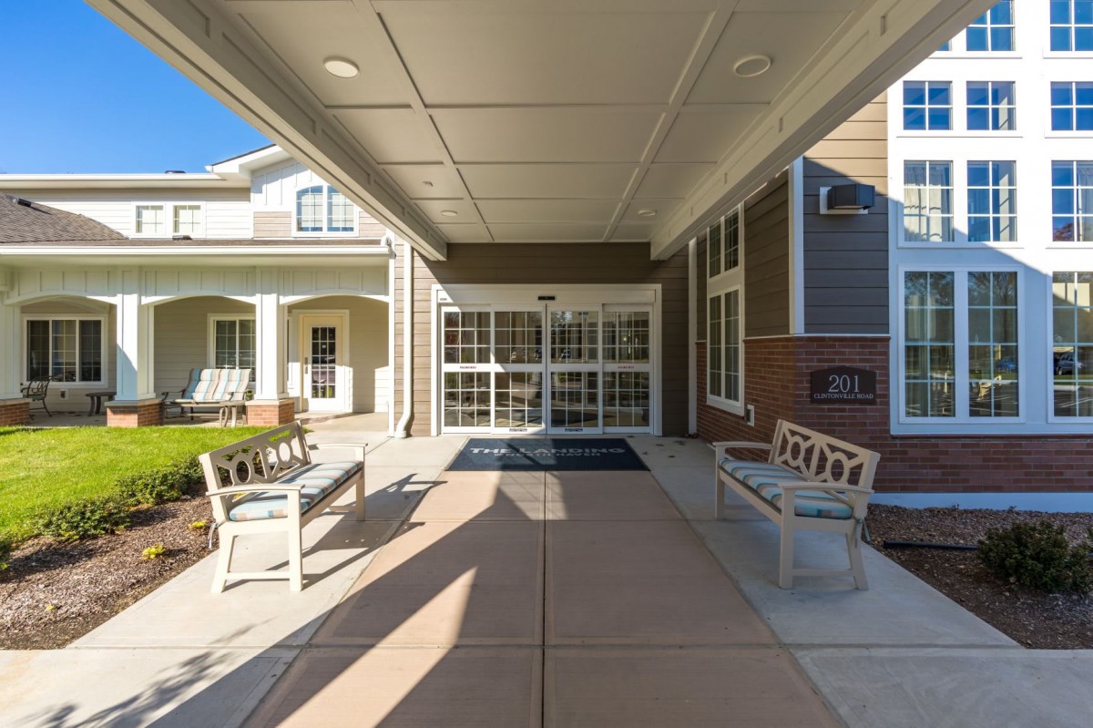 A covered outdoor entrance with benches leading to a building under a sunny sky.