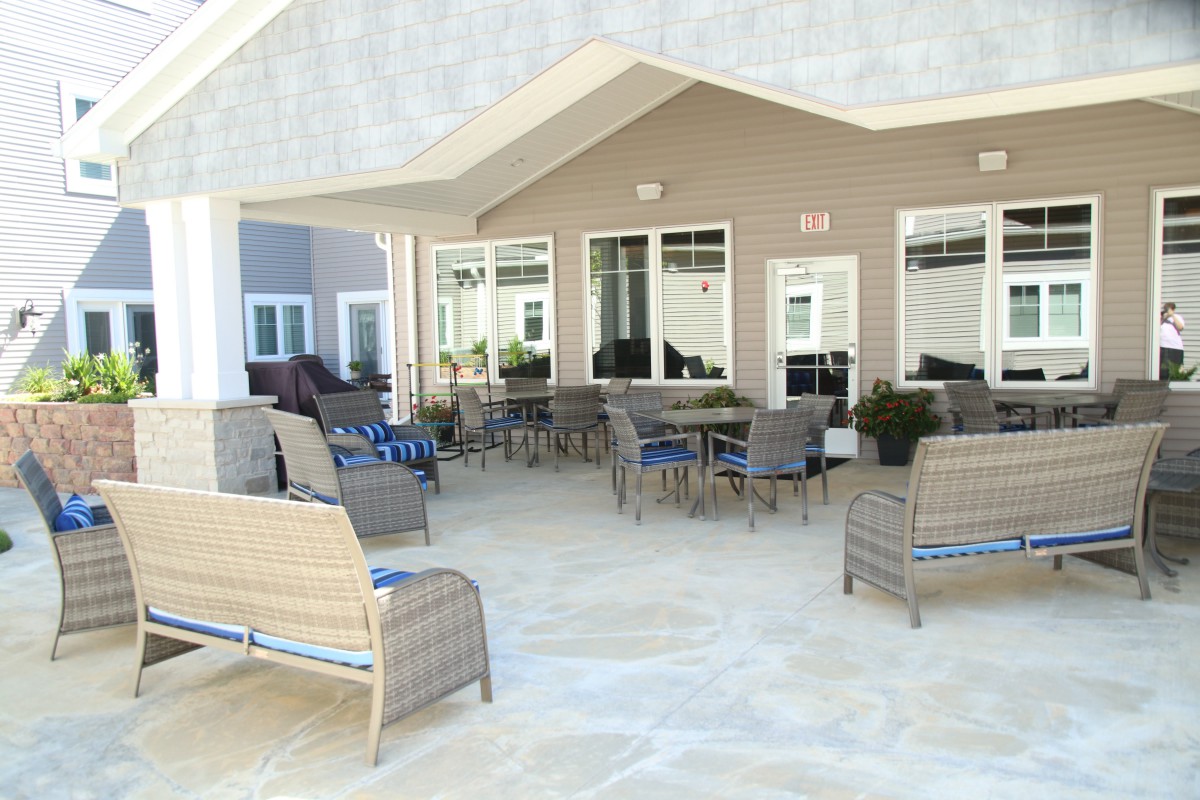 A spacious outdoor patio with wicker furniture and tables under a covered area.