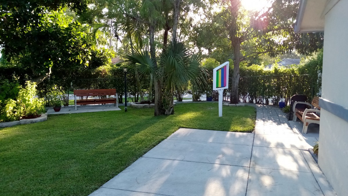 A serene park setting with a pathway, benches, and lush greenery.