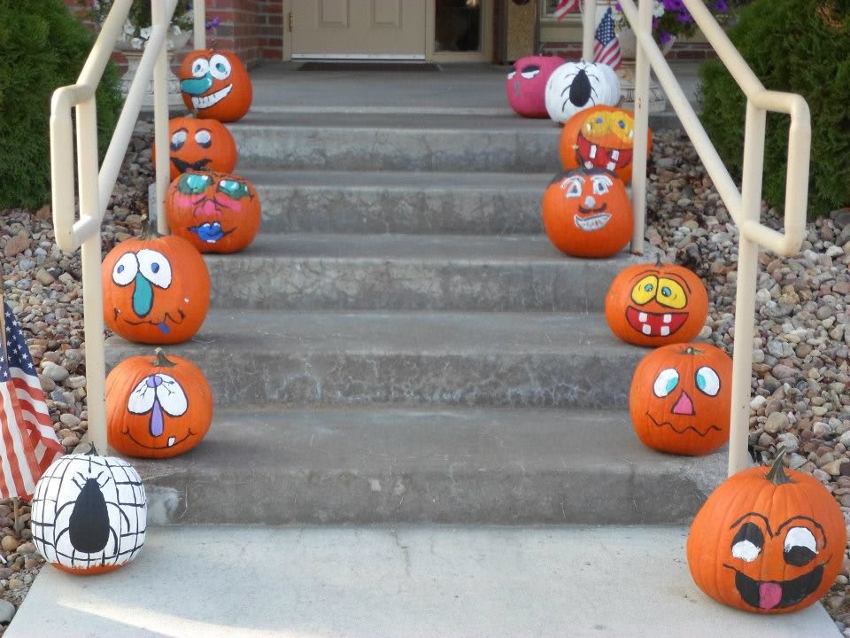 A collection of creatively decorated pumpkins with various expressive faces lined up on the stairs.