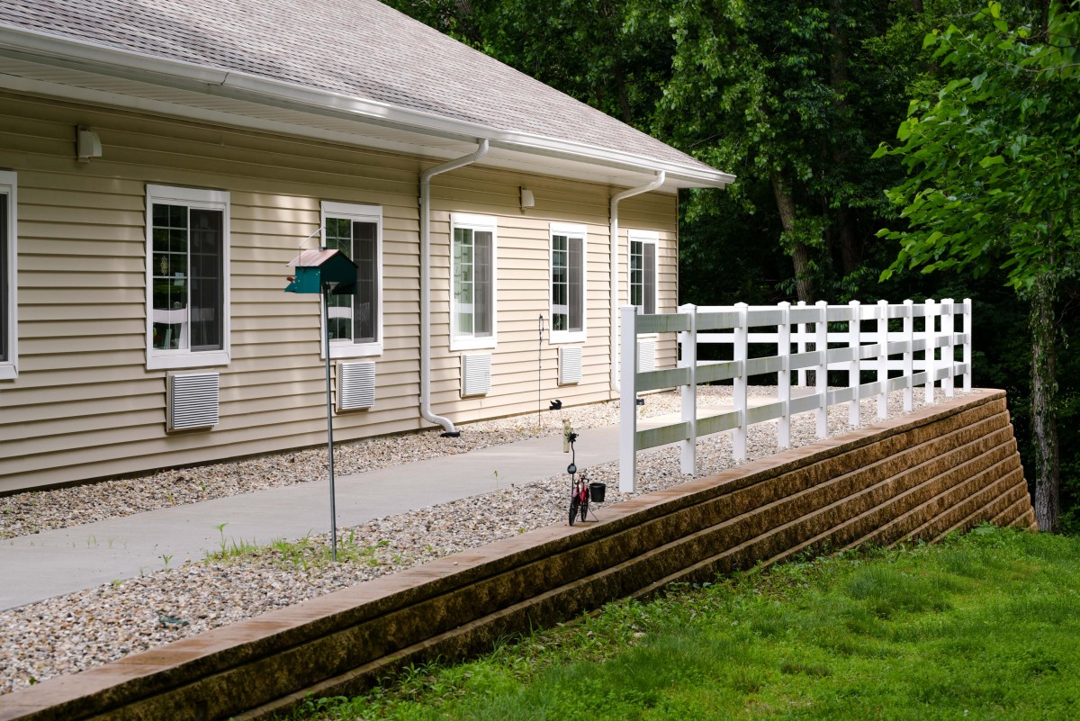 A house with a well-maintained yard and white fencing.