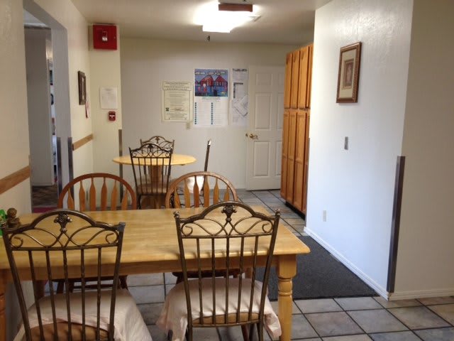 A cozy dining area with wooden tables and chairs, featuring wall decorations in a home-like setting.