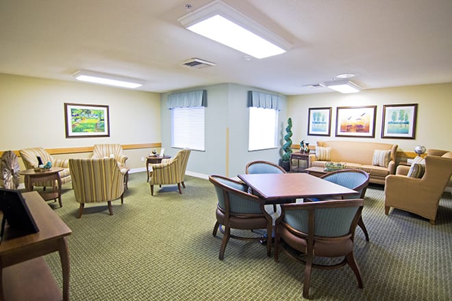 A cozy seating area with tables, chairs, and artwork on the walls.