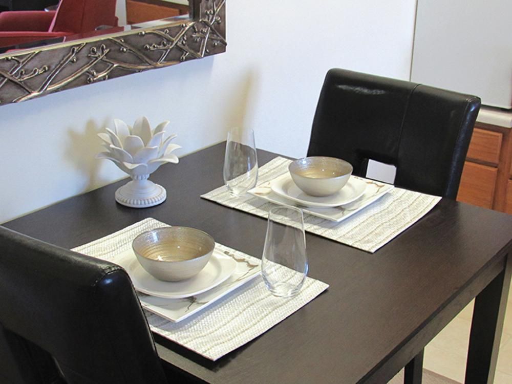 A modern dining table set for two with minimalist dinnerware and glassware.