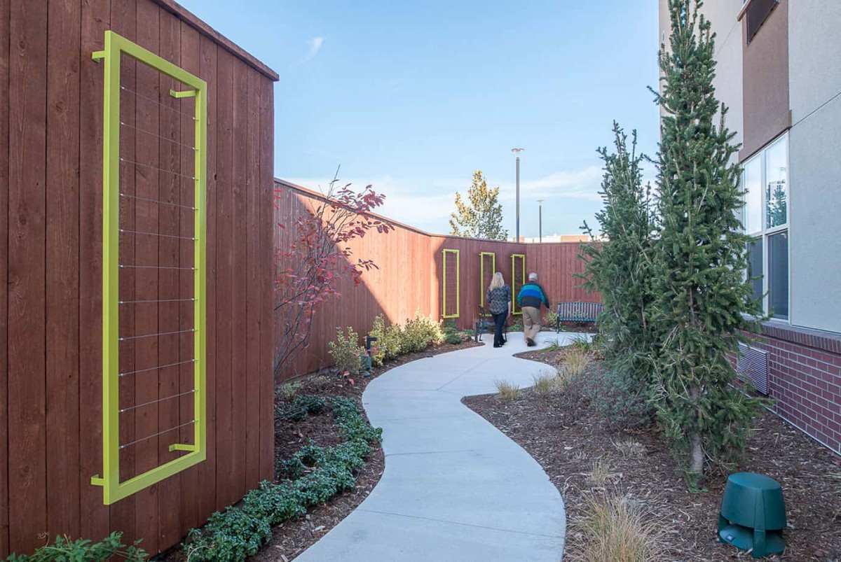 A modern outdoor garden with a winding pathway between architectural wooden structures.