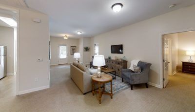 A cozy living room featuring a comfortable sofa, armchair, and a TV mounted on the wall.