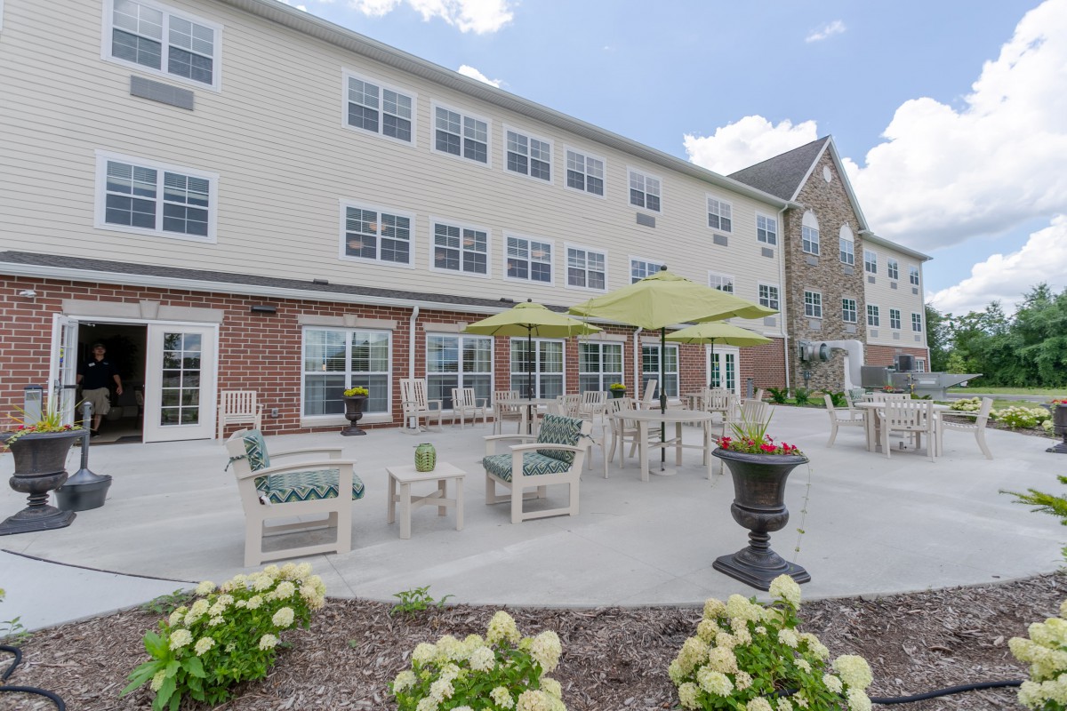 A well-maintained patio area with outdoor seating and umbrellas in front of a residential building.