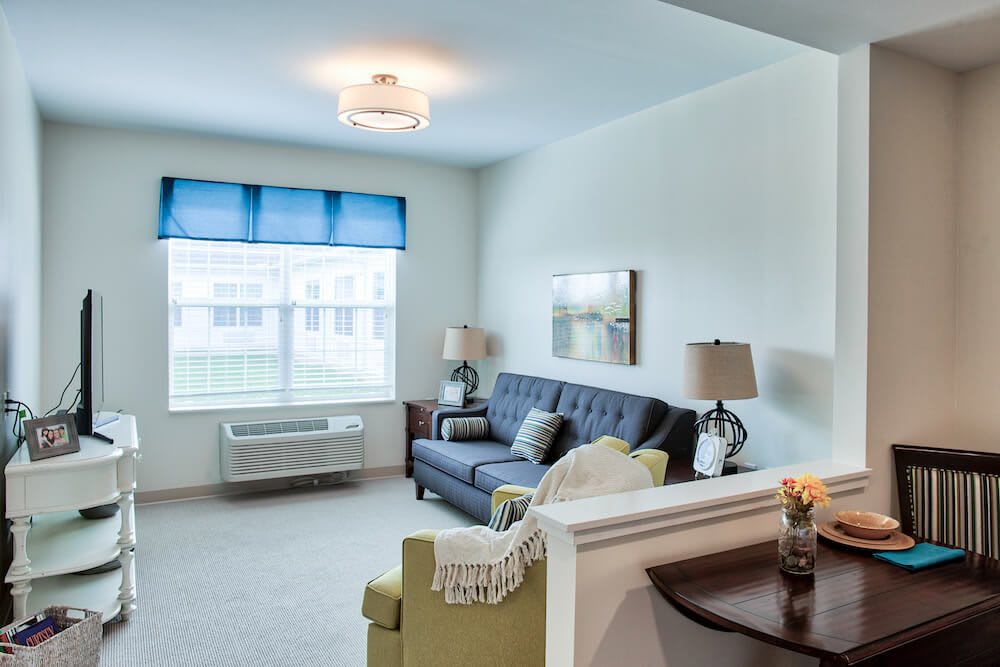 A cozy living room with a blue sofa, bright window treatments, and elegant decor.