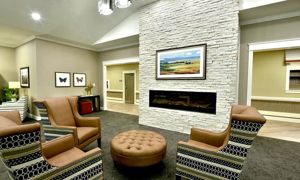 A modern living room with a cozy seating area around a sleek fireplace, featuring artwork and stylish decor.