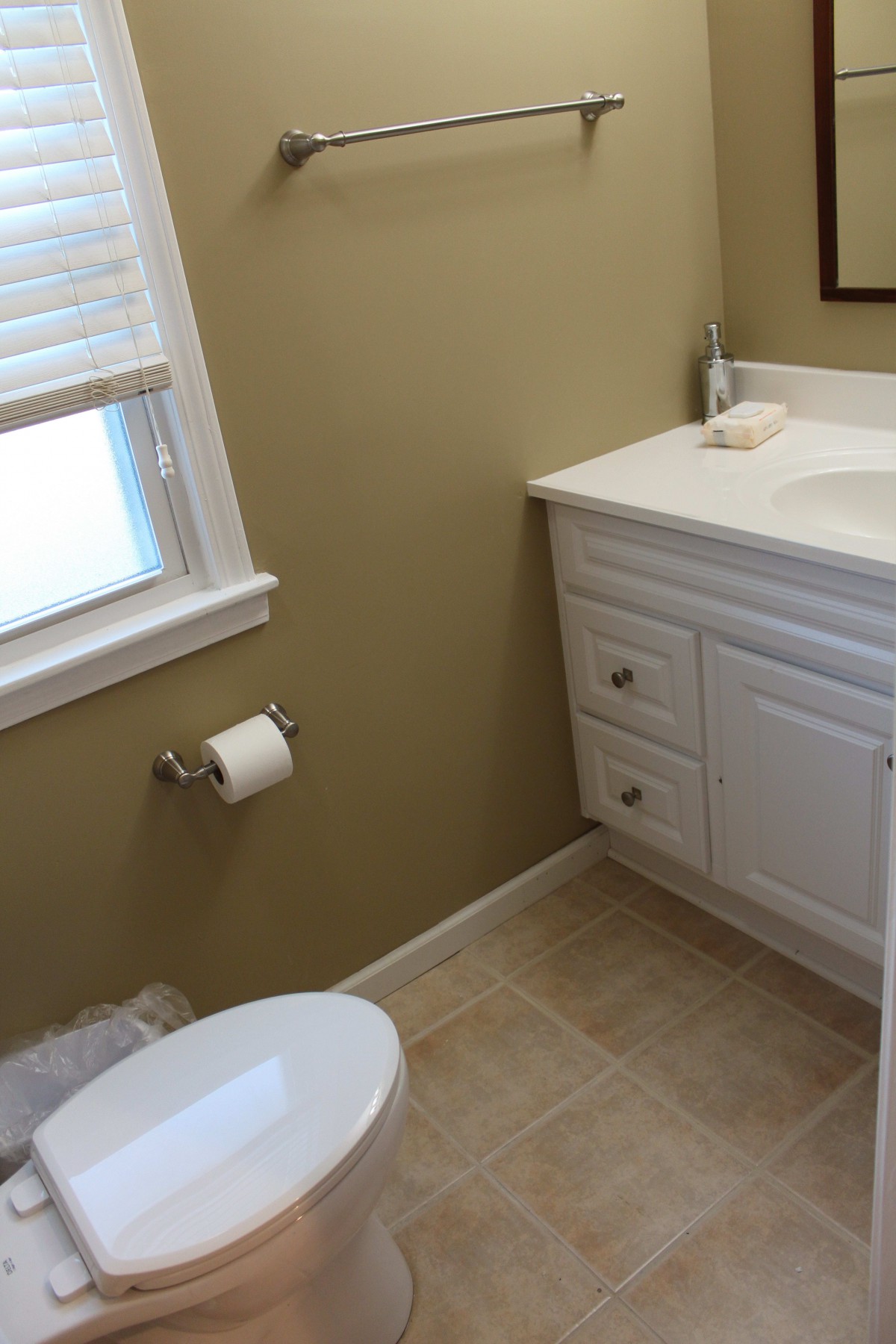 A small bathroom with a white vanity and tiled floor.