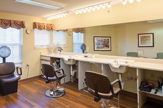 A bright barber shop interior with chairs, mirrors, and sinks lined up along the counter.