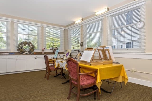 A bright art studio with tables and easels set up for painting.