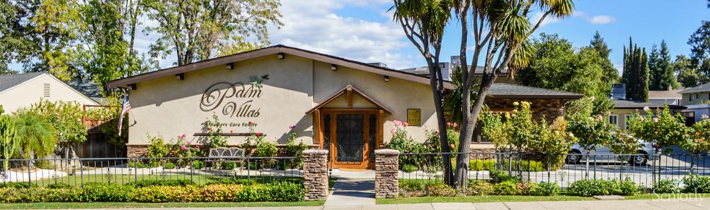 A well-maintained house with a wooden entrance surrounded by lush greenery and trees.