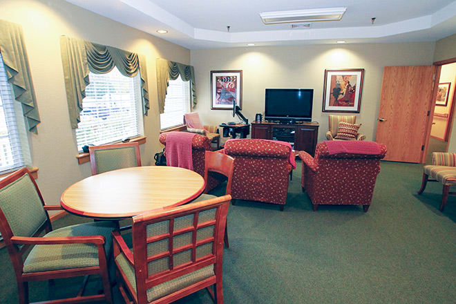 A cozy living room with comfortable seating, a television, and a round table by the window.