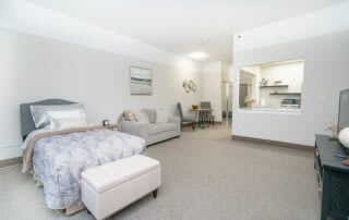 A modern studio apartment with a cozy bed, seating area, and minimalist decor.