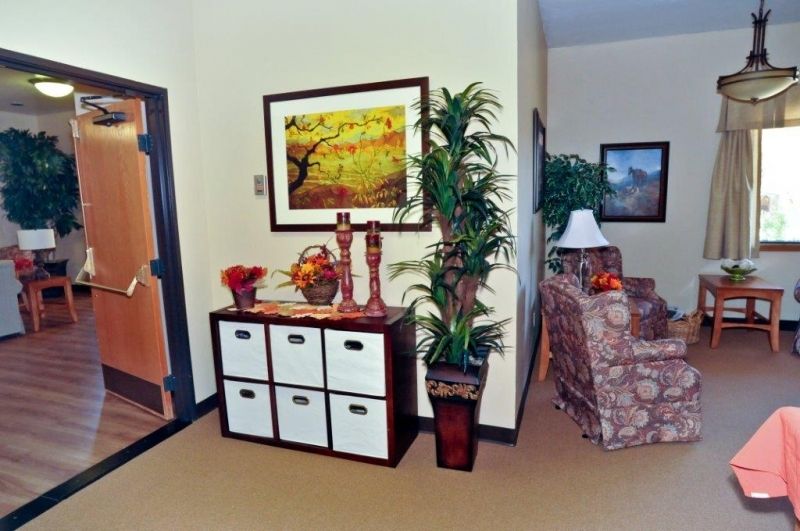 A cozy living room corner with a decorative sideboard, framed artwork, and indoor plants.