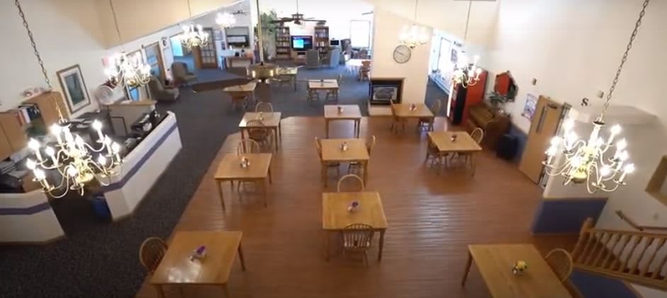 An empty restaurant dining area with neatly arranged tables on a wooden floor.
