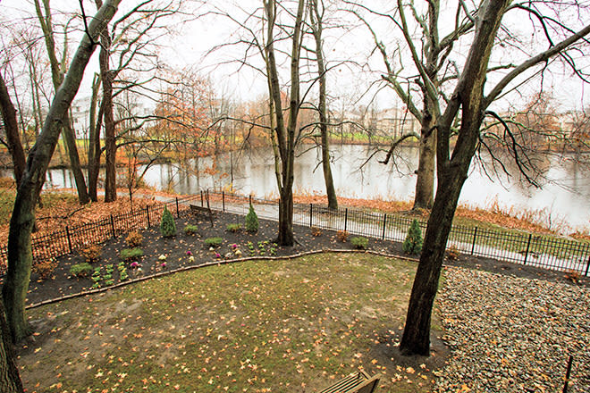 A serene autumn scene by the lake, with a pathway lined by bare trees and fallen leaves.