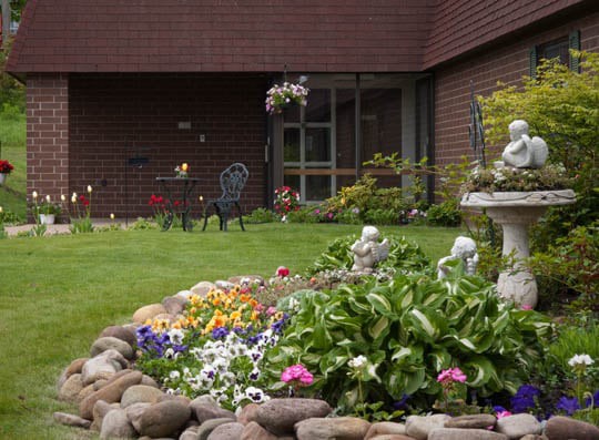 A beautifully maintained garden with colorful flowers, decorative statues, and a lush green lawn.