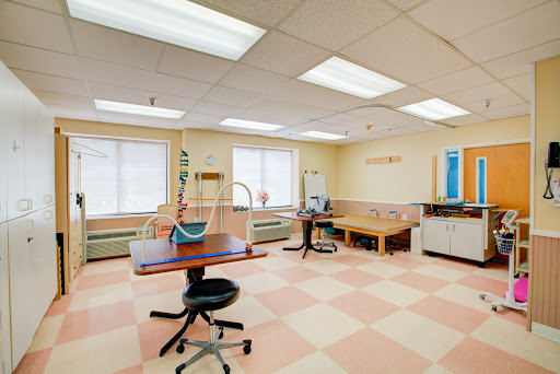 A spacious, well-lit medical clinic interior with various equipment and furniture.